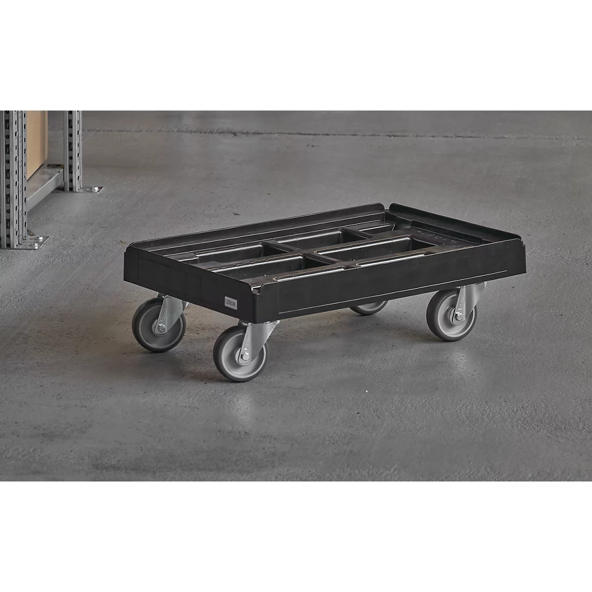 Black transport trolley with four wheels stands on gray floor. An empty shelf is seen in the background.