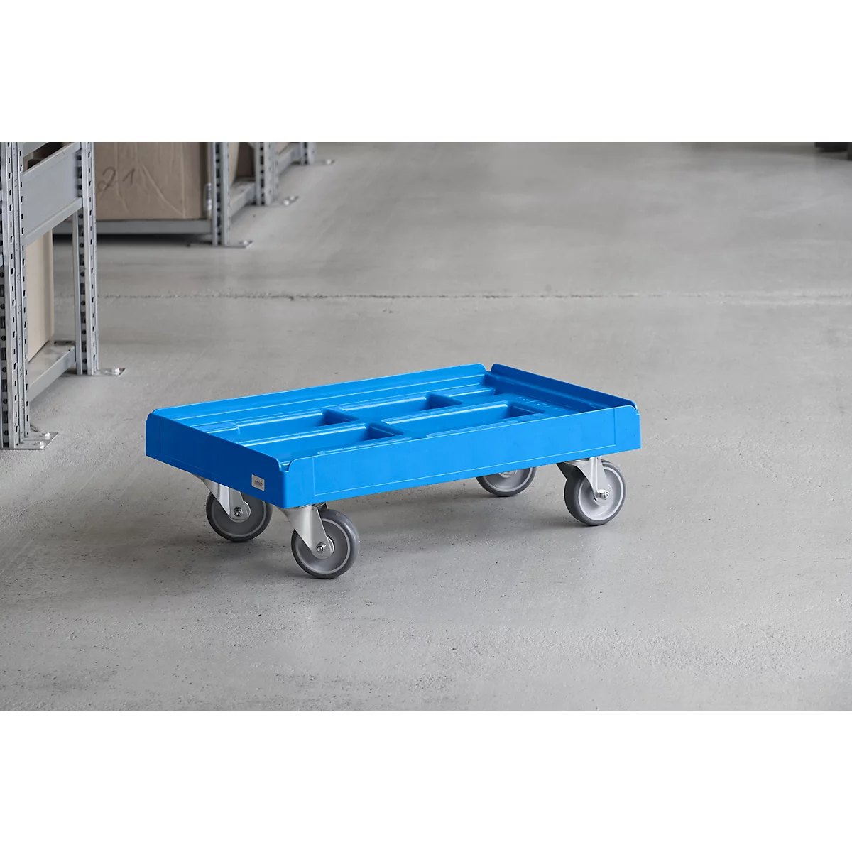 Blue trolley in warehouse. The cart stands on four wheels and has a rectangular loading area.
