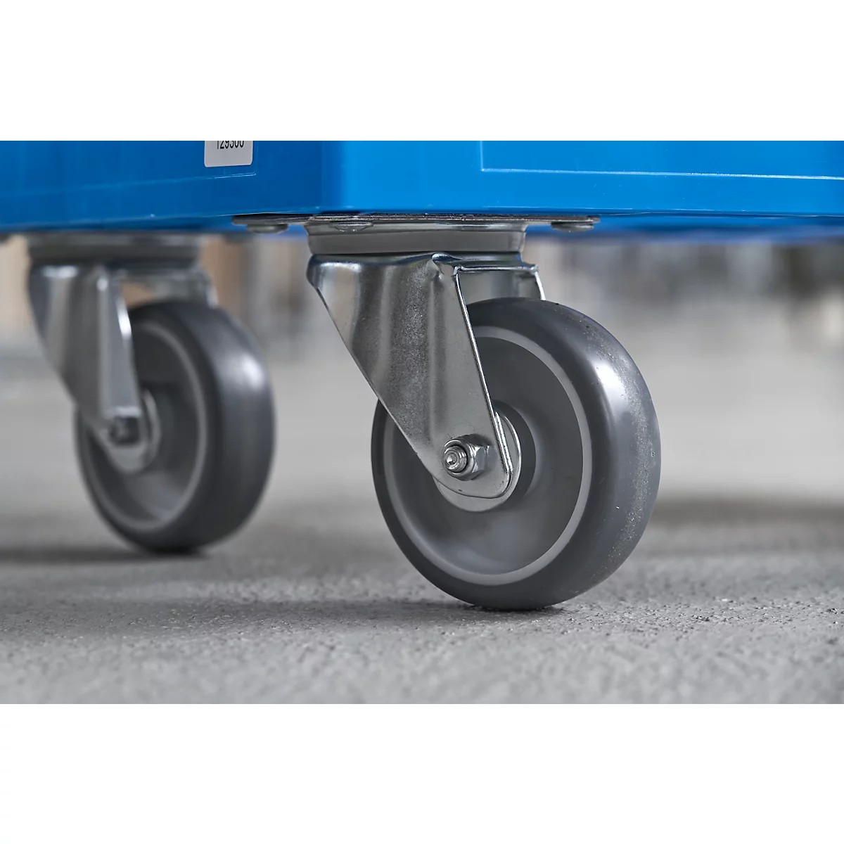 Close-up of two castors on a blue container. The castors are made of metal and rubber.
