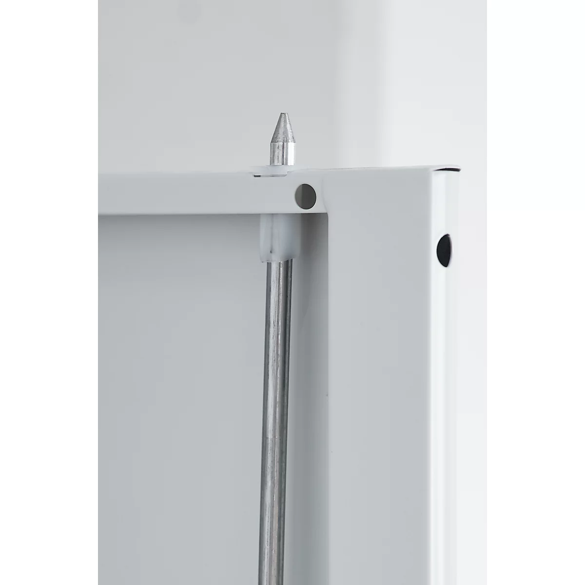 Close-up of a white frame with silver pin and pole. A hole and the tip are visible.