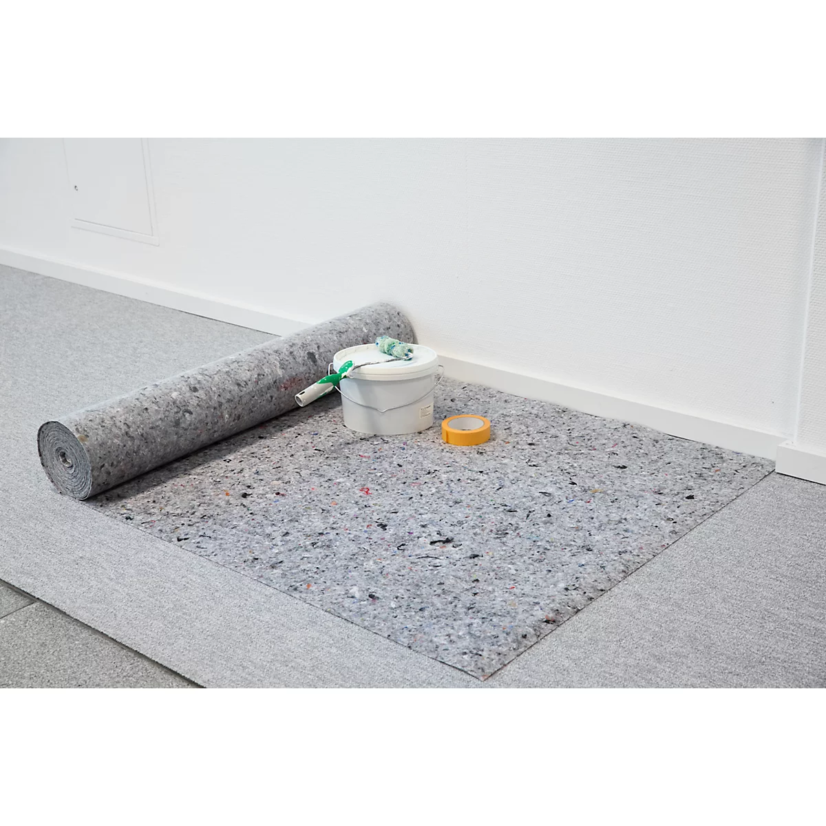 Eine Rolle Dämmvlies liegt auf einem Boden, daneben ein Farbeimer, eine Rolle und Klebeband.