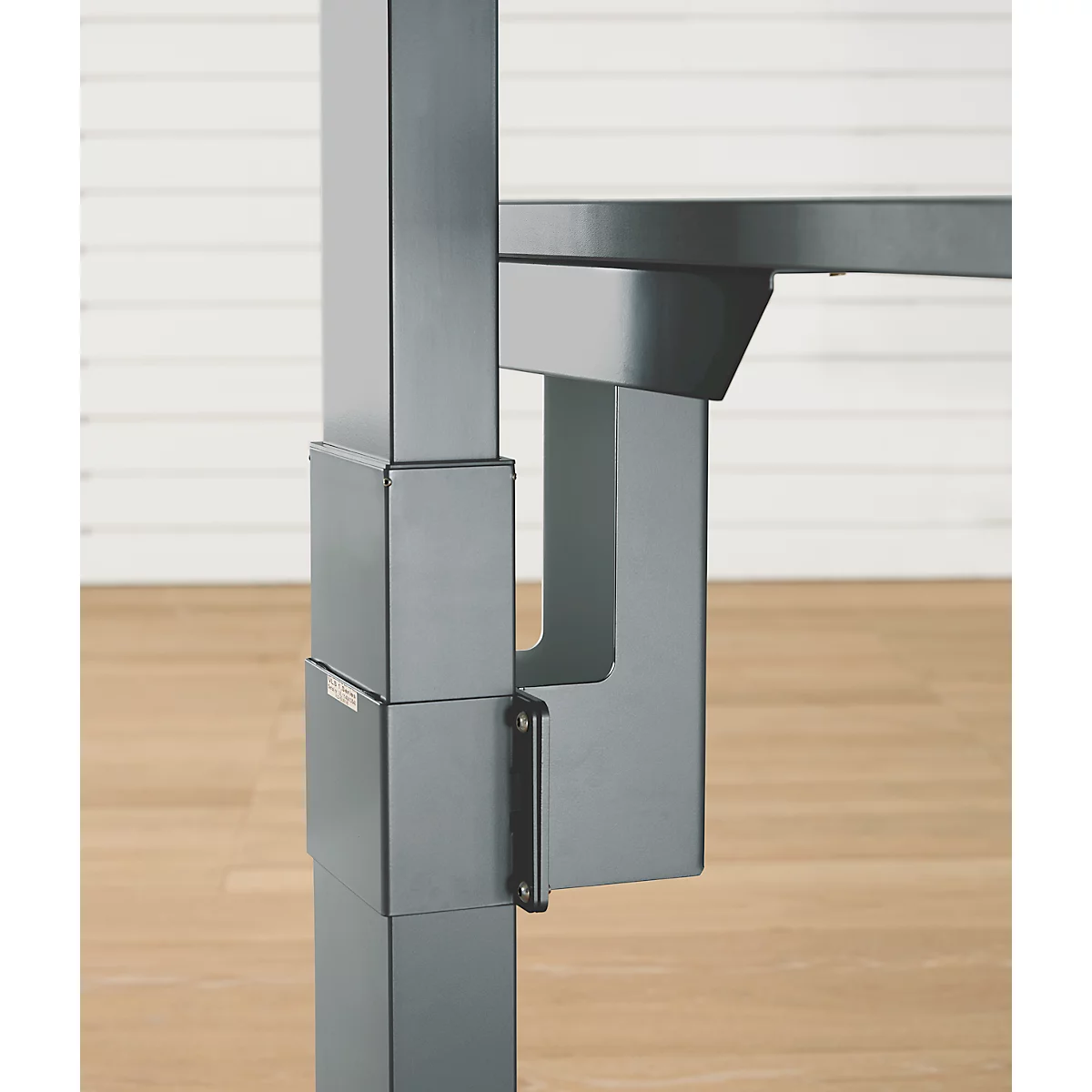 Gros plan détaillé d'un pied de table métallique. La jonction d'angle et le mécanisme de réglage en hauteur sont clairement visibles.