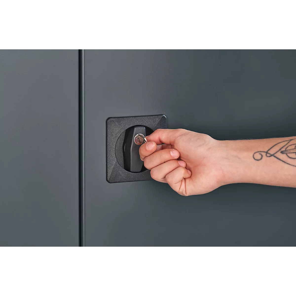 Gros plan: Personne ouvrant une porte d'armoire verrouillée. La main insère la clé dans la serrure. Il y a un tatouage sur le bras.