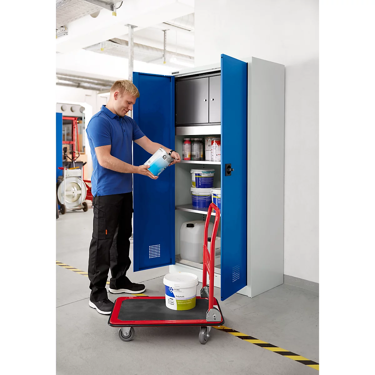 Un homme en bleu ouvre une armoire bleue et y place un pot de peinture. Un diable est devant.