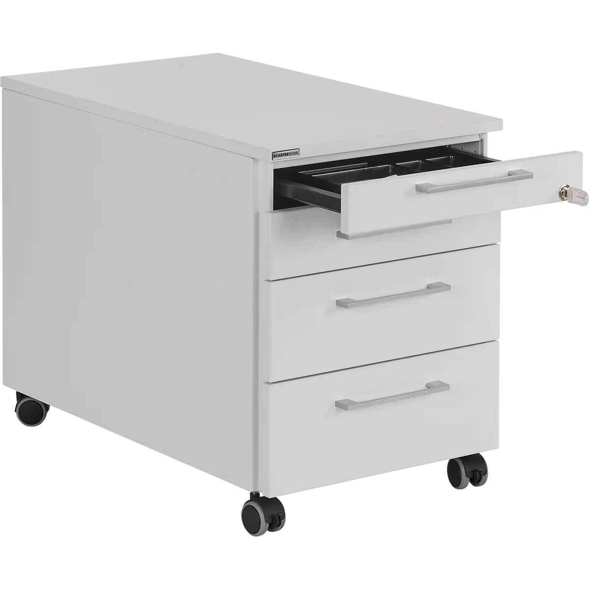 Cajonera blanca con tres cajones. El cajón superior está abierto, mostrando compartimentos para material de oficina. Una llave cuelga del cajón.