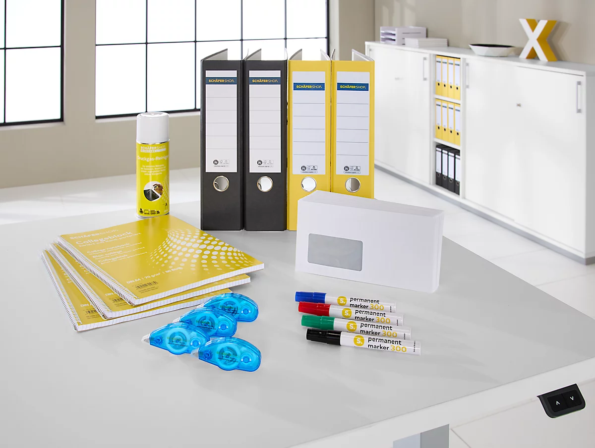 Escritorio con carpetas amarillas, blocs de notas, bolígrafos, barras de pegamento y sobre.