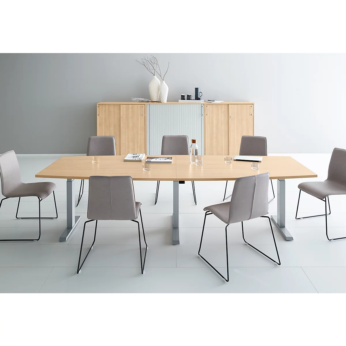 A conference table with chairs in a modern office. There are water bottles and glasses on the table.
