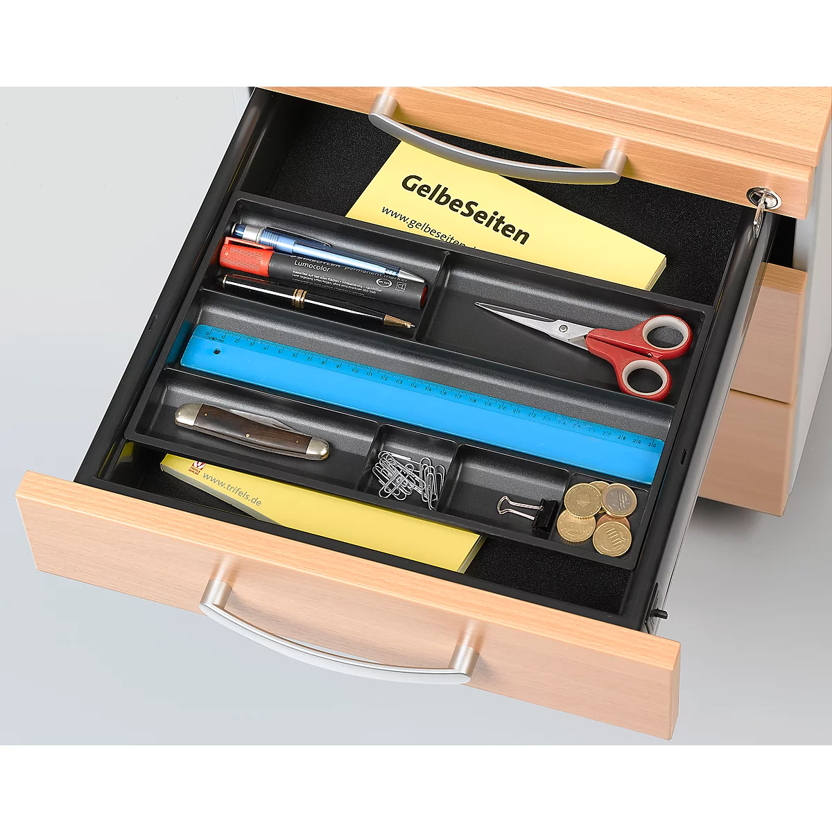 Open drawer with office supplies: scissors, ruler, pens, money, staples, and notepad.