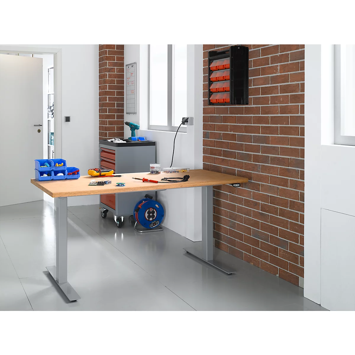 Workbench in workshop with tools. Tool box, tools, drill and cable reel.