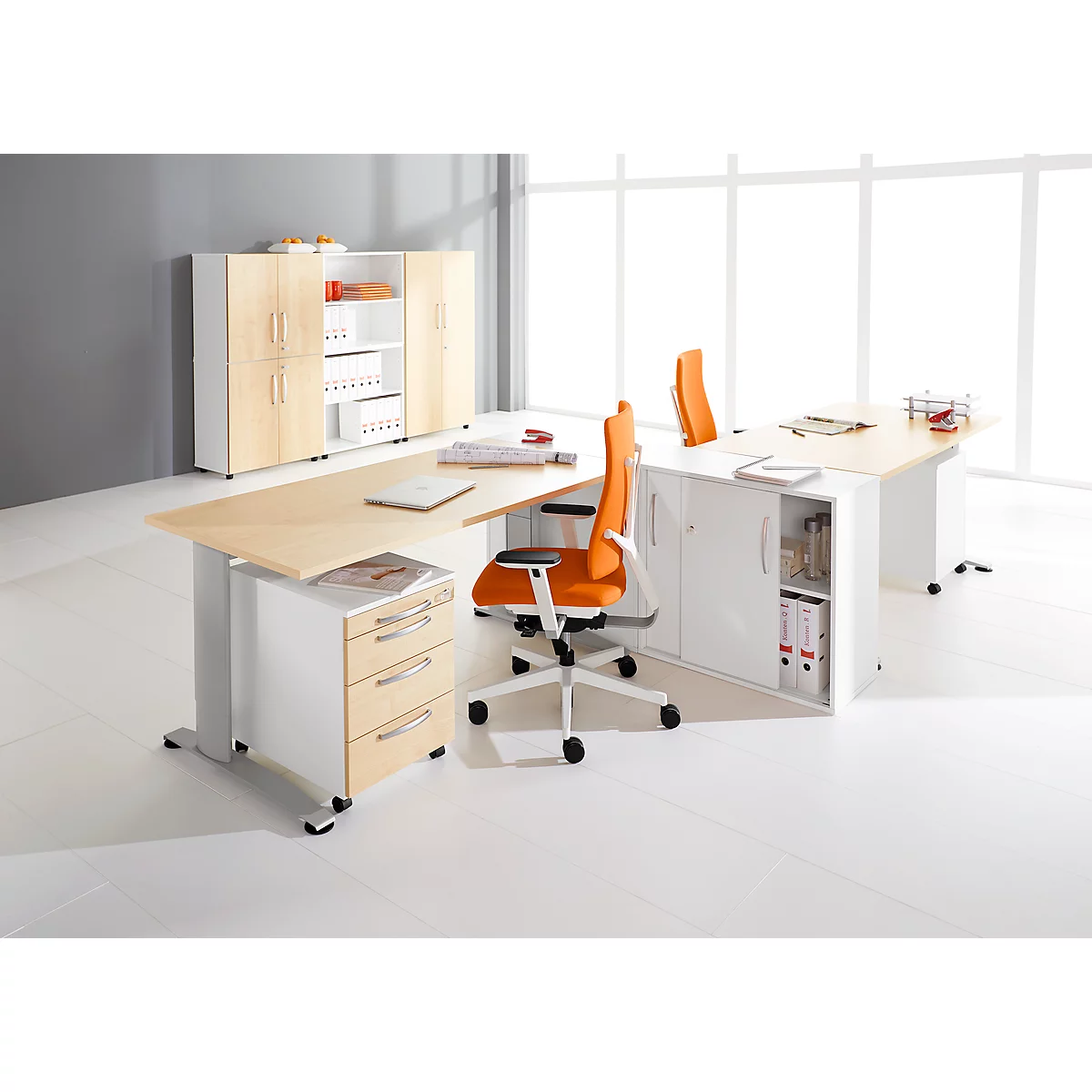 Kantoor met groot bureau, ladekast, oranje stoelen en opbergruimte. Heldere ambiance.