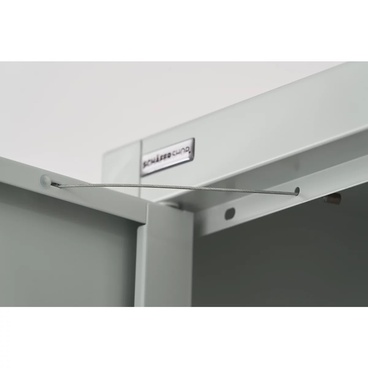 Close-up of a corner section of a cabinet, light grey. A wire is stretched.