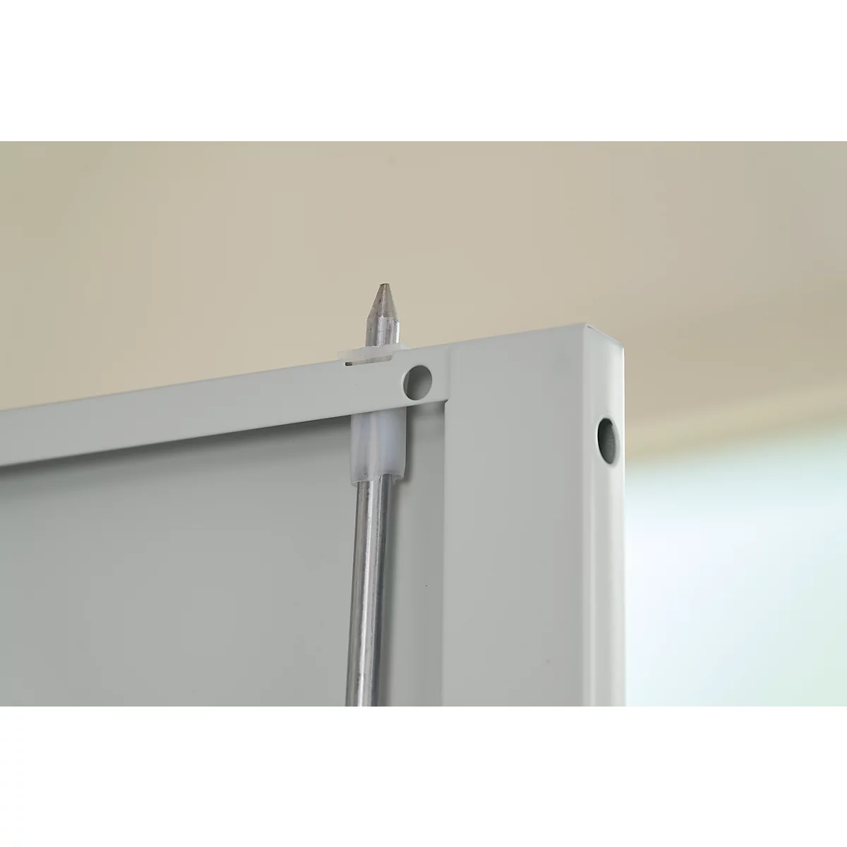 Close-up of a silver pin being inserted through a hole in a white metal structure.