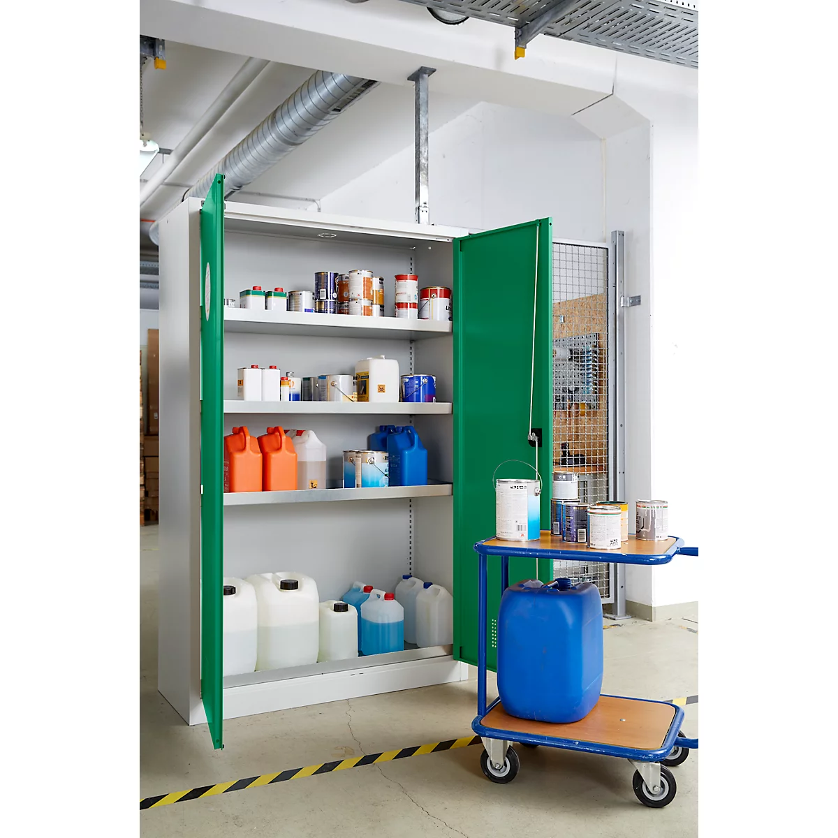 Open kast gevuld met chemische containers; een trolley met verfblikken en een blauwe ton staan ernaast.