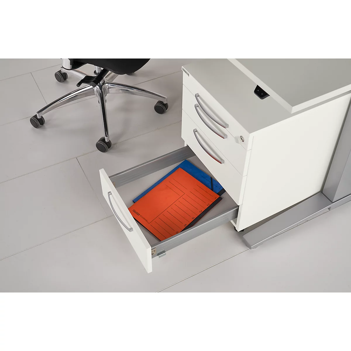 Desk with an open drawer. Inside, a red and blue folder.