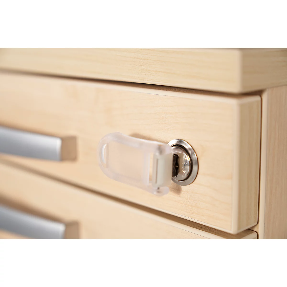 Close-up of a cabinet with a transparent key and a silver handle. The cabinet is made of light-colored wood.