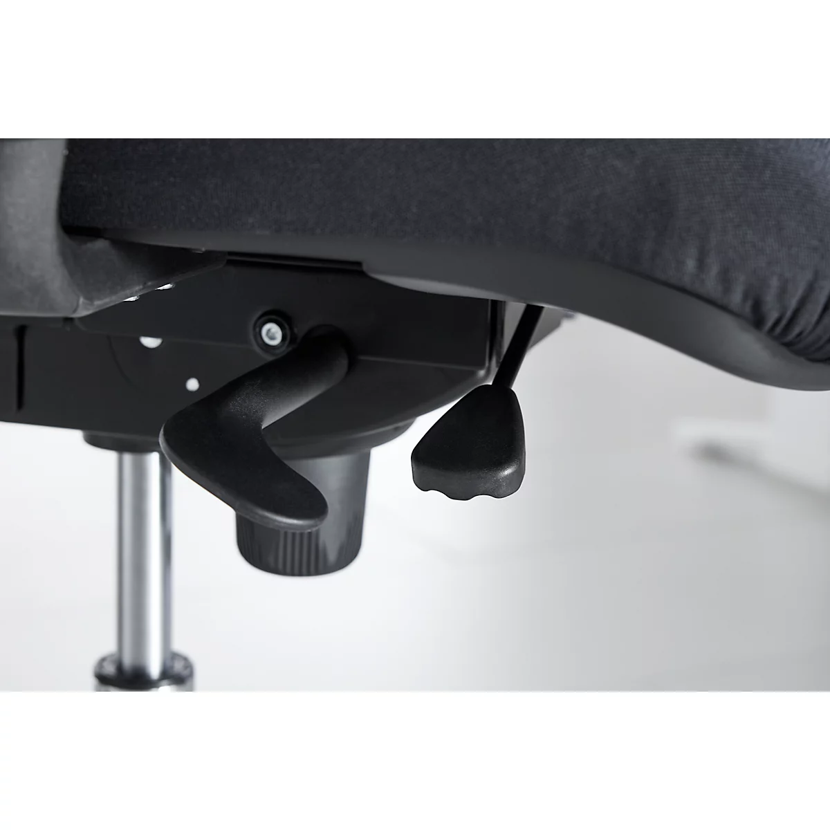 Detail view of the lower part of an office chair. The chair is black with an adjustable lever mechanism.