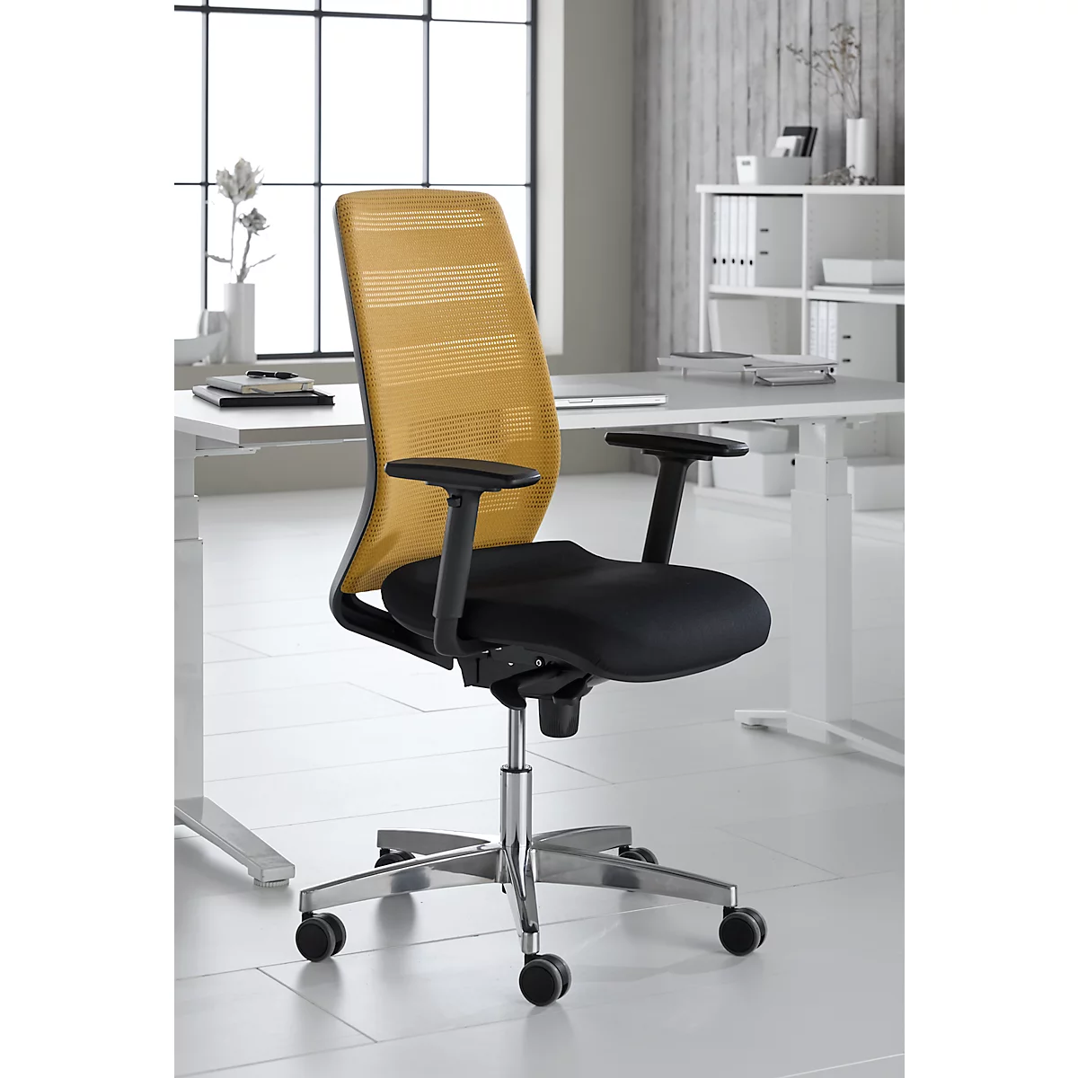 Office chair with yellow backrest, black seat and armrests, in front of a light background.