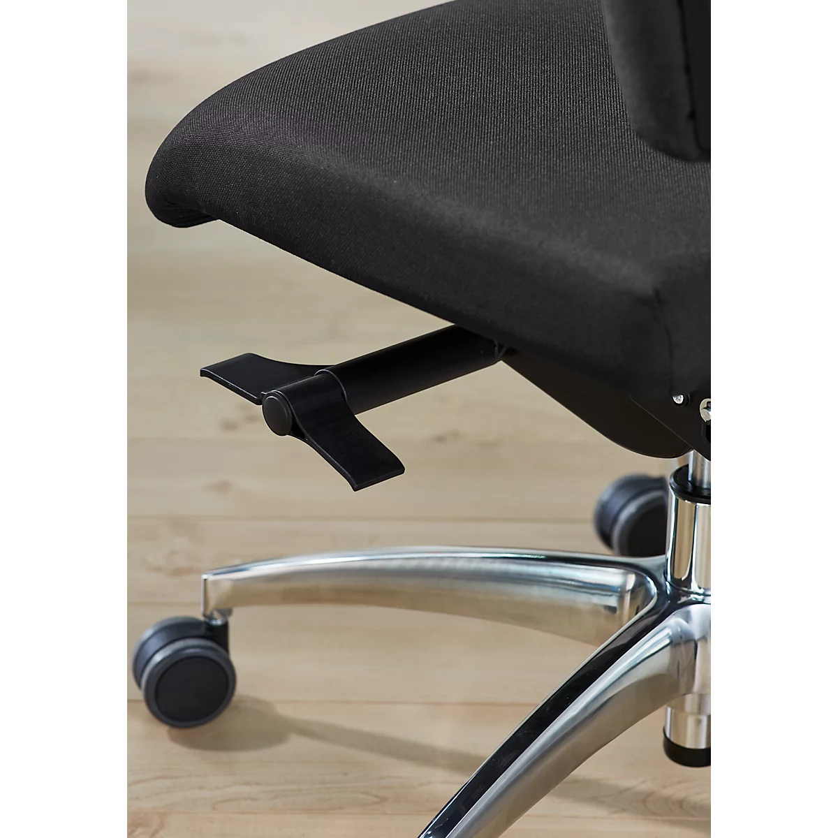 Close-up of a black office chair with adjustable controls on wheels on a wooden floor.