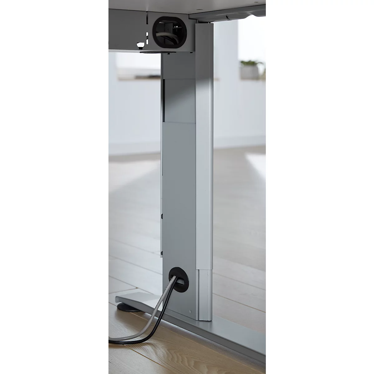 Close-up of a gray, height-adjustable desk leg. Cables run through openings in the leg.