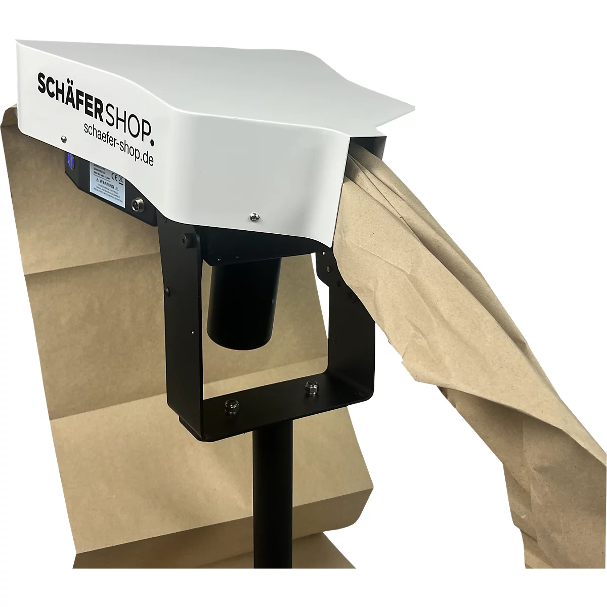 Een apparaat voor papieren zakken. SCHÄFER SHOP staat op het witte gedeelte. Een bruine papieren zak komt uit de opening.