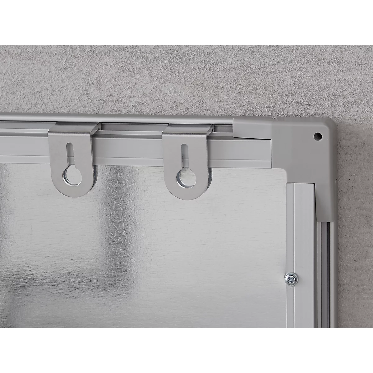 Primer plano de un tablero plateado con colgadores fijados a una pared.