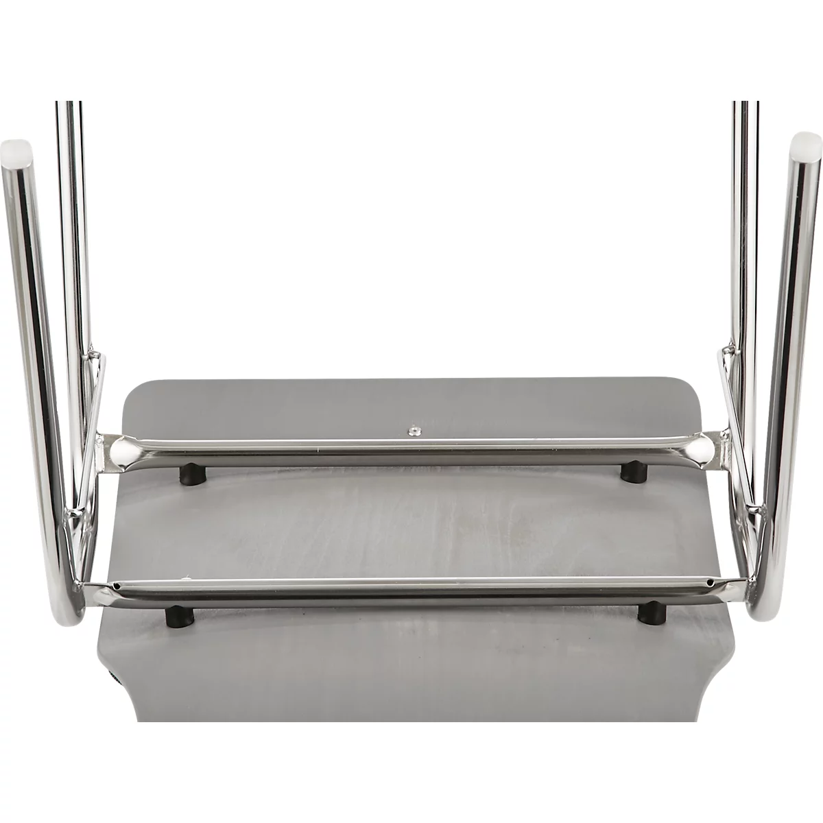Stoel gefotografeerd van onderaf. Grijze zitting, metalen frame, zwarte rubberen voetjes.