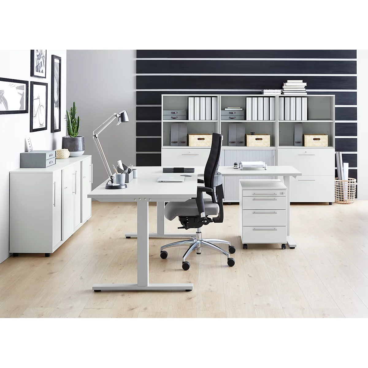 Bright office space with white desk, chair, cabinets, and grey wall. A modern, functional work environment.
