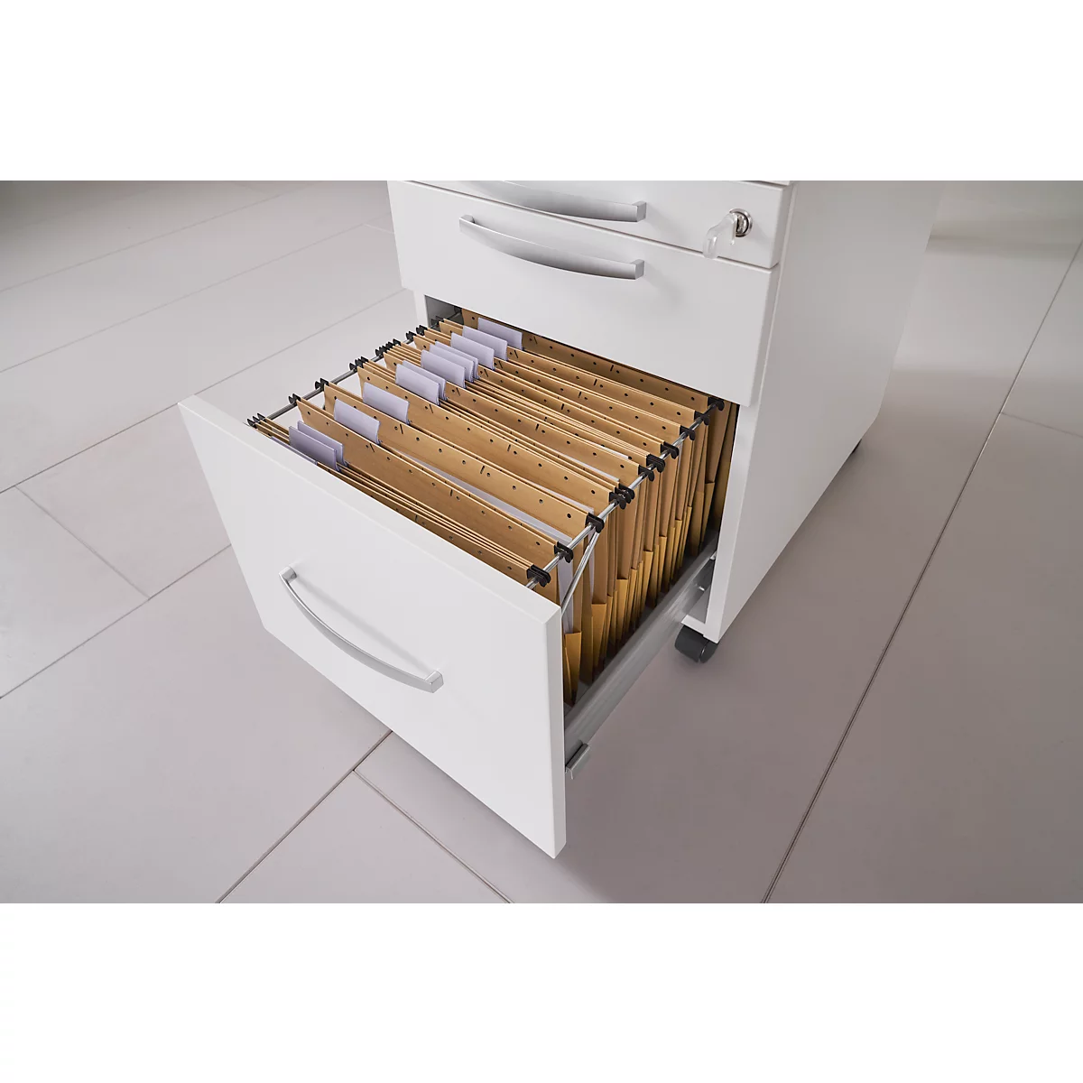 White filing cabinet with open drawer and brown folders. The cabinet is on grey tiles.