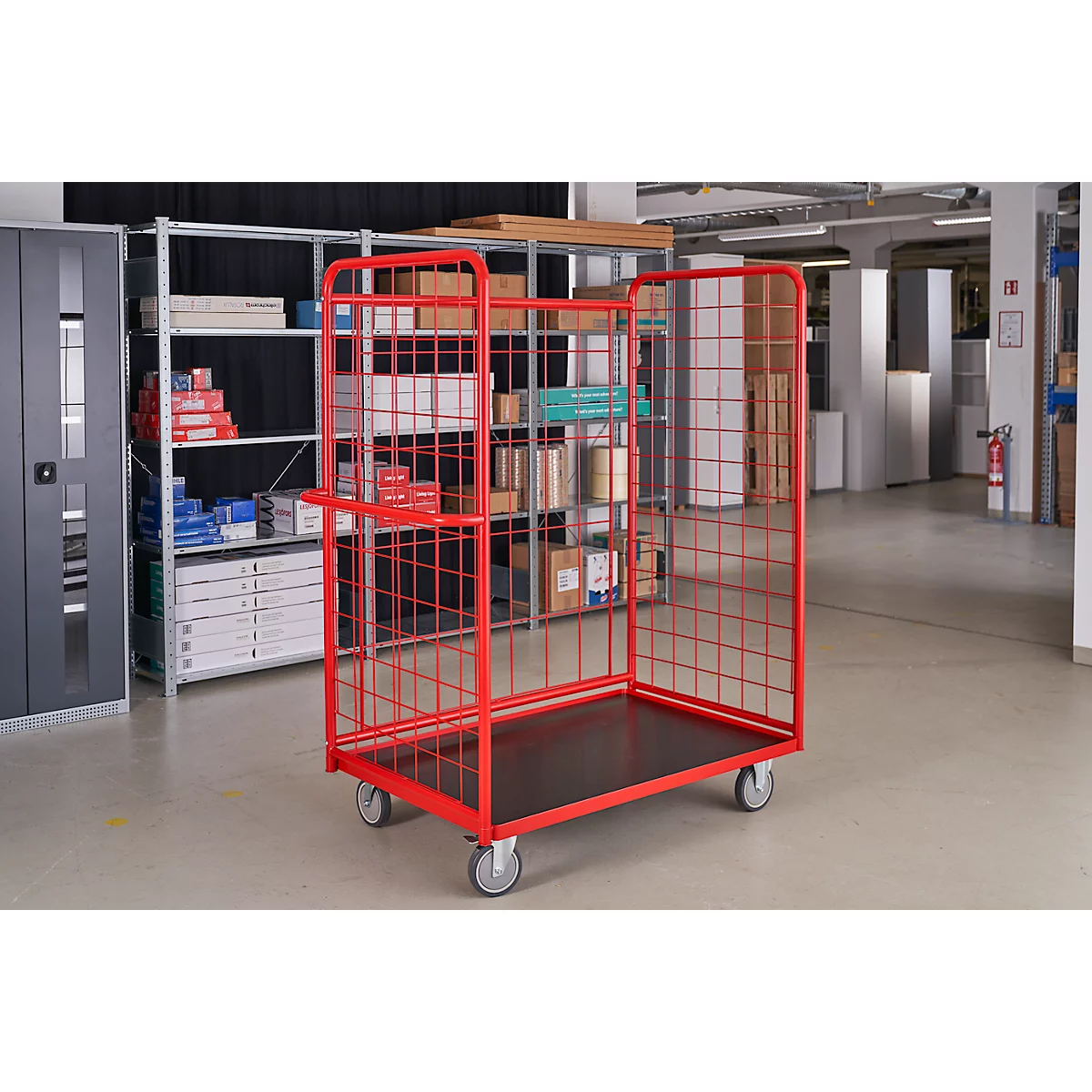 Red transport cart with grid, on wheels. In a warehouse, filled with goods.