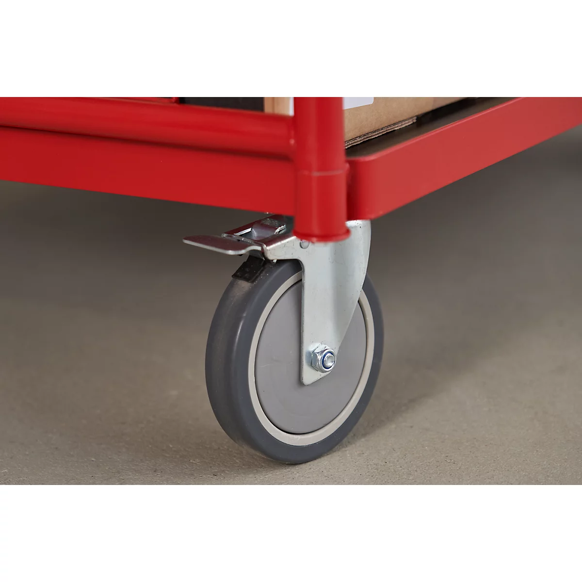 Close-up of a red cart with a gray wheel and black stopper.