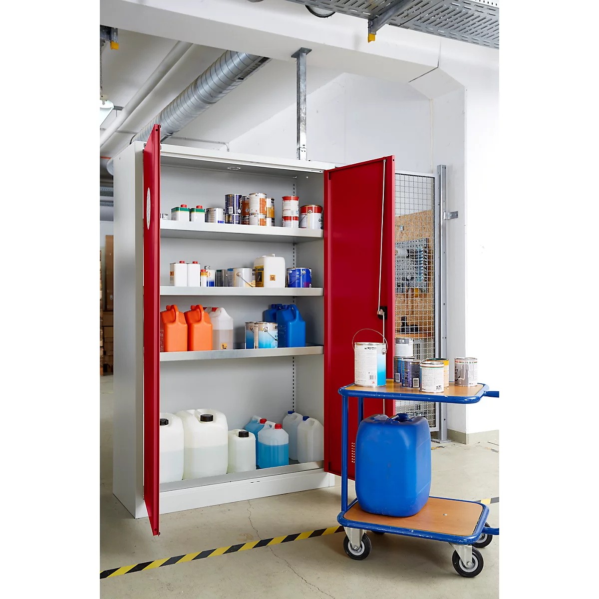 Offener roter Schrank mit Chemikalien und Farben, daneben ein blauer Kanister auf einem Servierwagen.