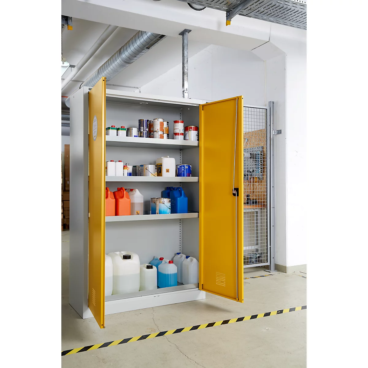 Offener gelber Schrank mit Chemikalien und Behältern, Warnmarkierung am Boden.