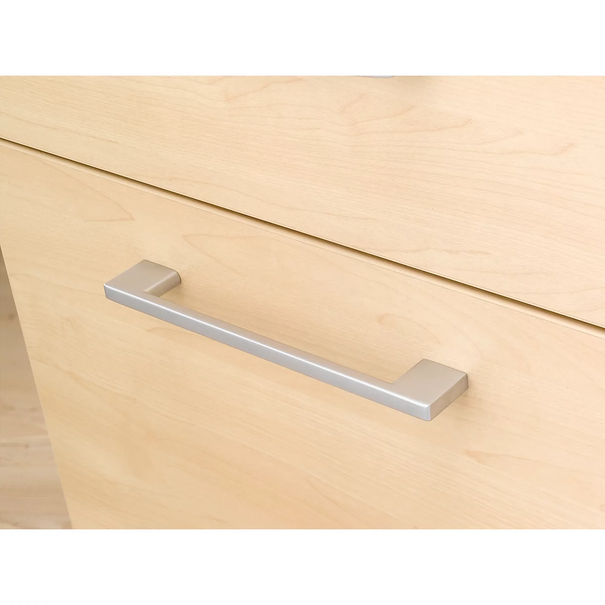 Close-up of a light wooden drawer with a silver handle.