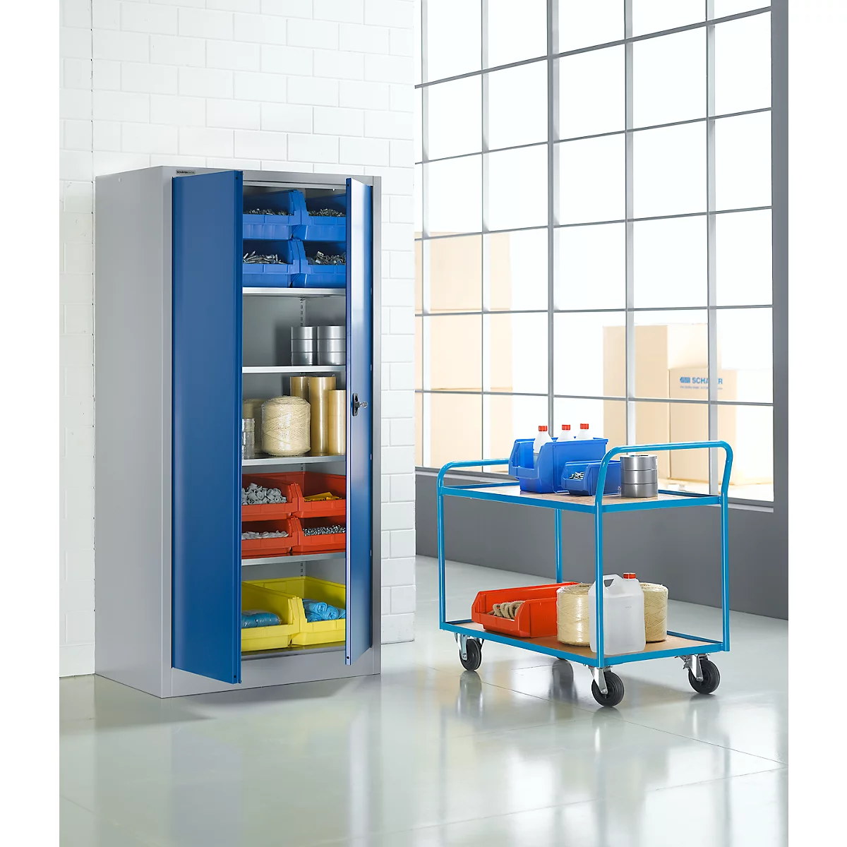 Grauer Metallschrank mit blauen Türen, gefüllt mit Behältern und Rollwagen mit Utensilien.