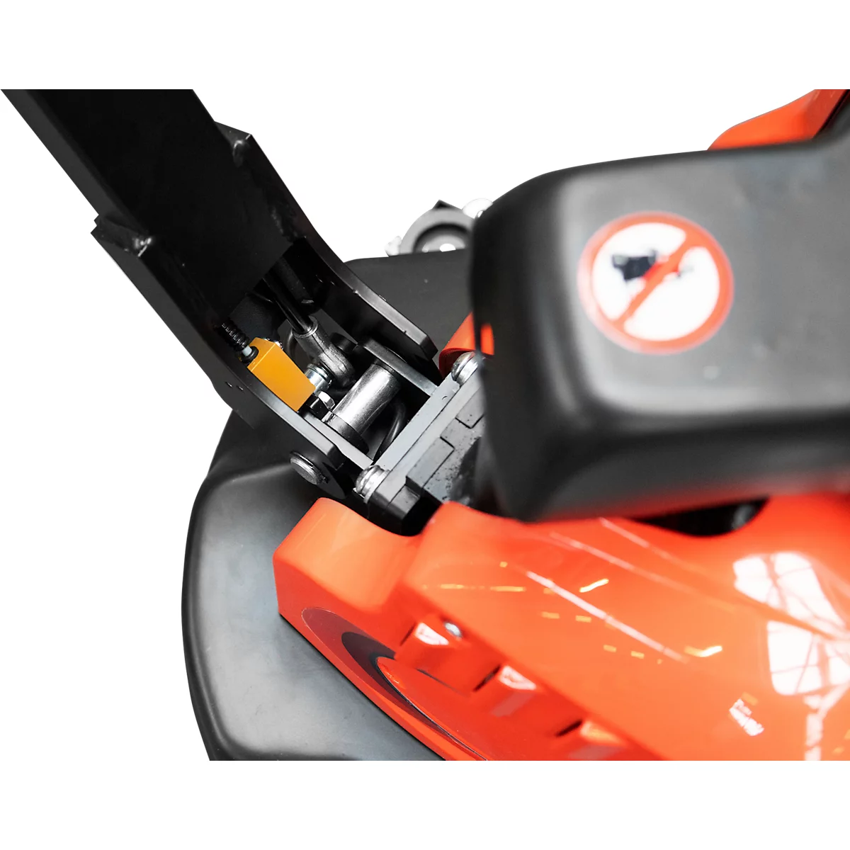 Detailed view of the mechanics of a lawnmower, with orange and black components. In the background a no-horn sign.