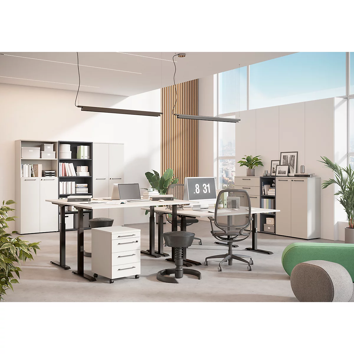 Büro mit höhenverstellbaren Schreibtischen, Bürostühlen und Schränken. Auf dem Monitor steht 8:31. In der Ecke steht eine grüne Couch.
