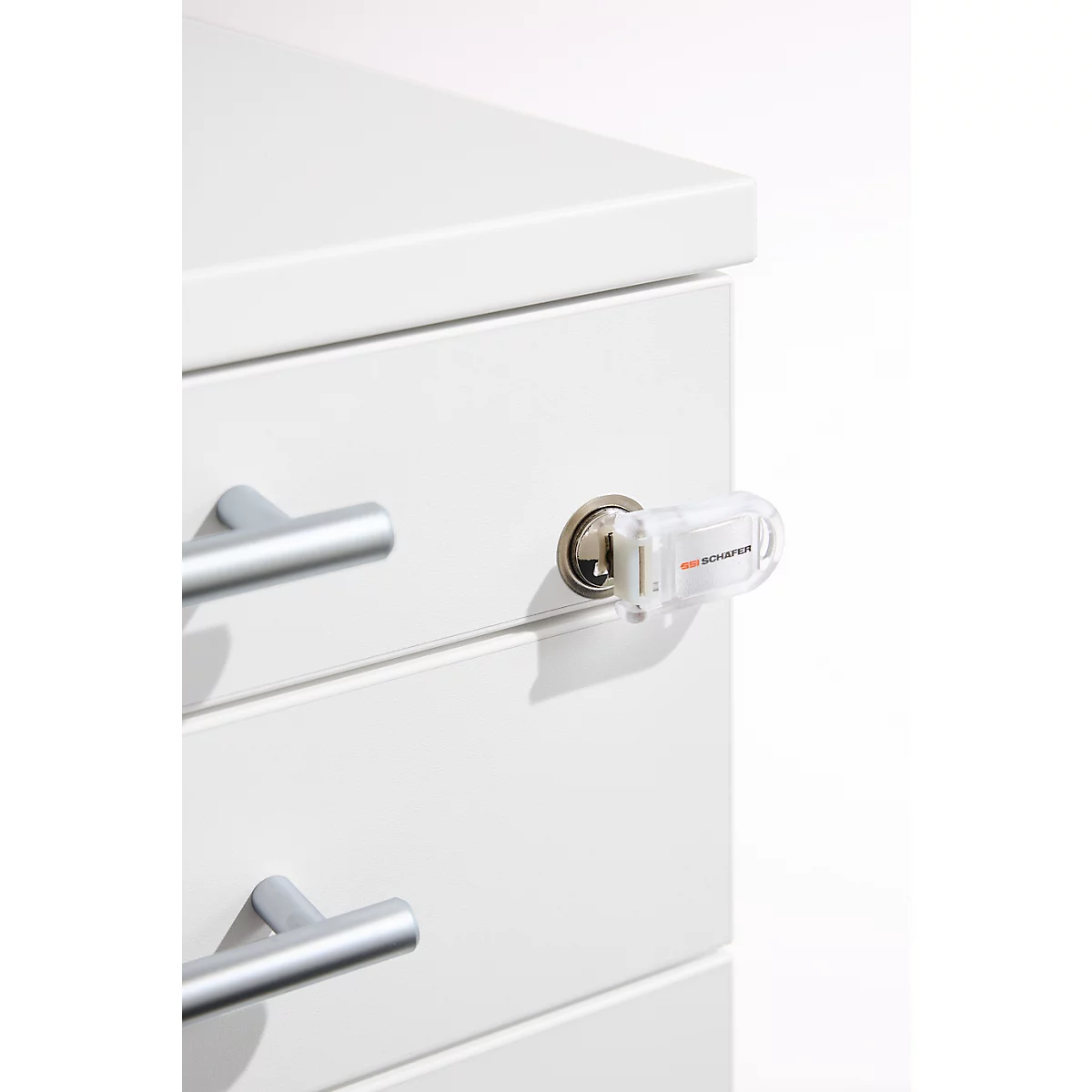 Detailaufnahme einer weißen Schublade mit silbernen Griffen und einem Schloss, in das ein transparenter Schlüssel steckt, mit der Aufschrift 'SECURE'.