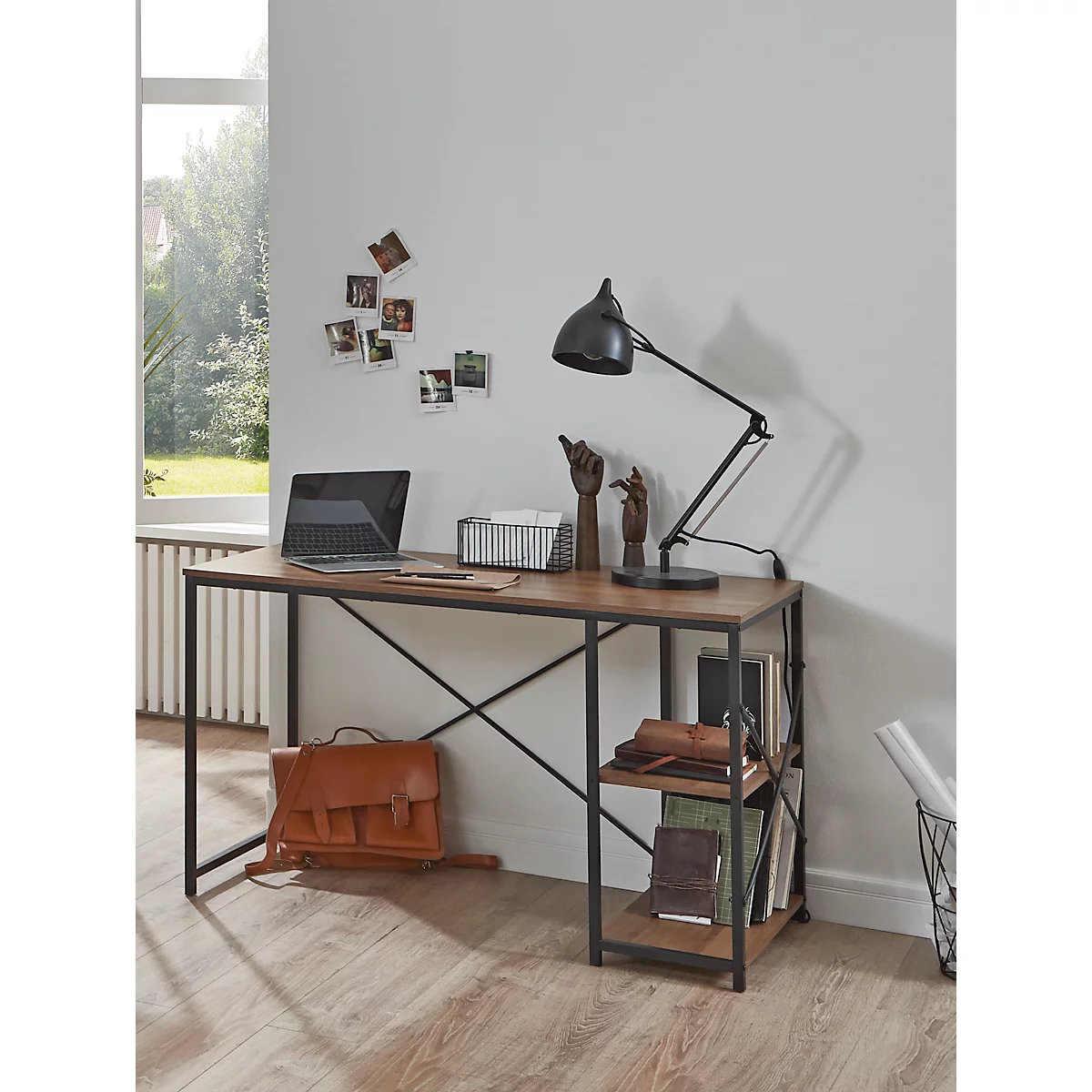 Schreibtisch mit Lampe und Laptop, stilvoll eingerichtet. Im Hintergrund Fenster und Fotos.