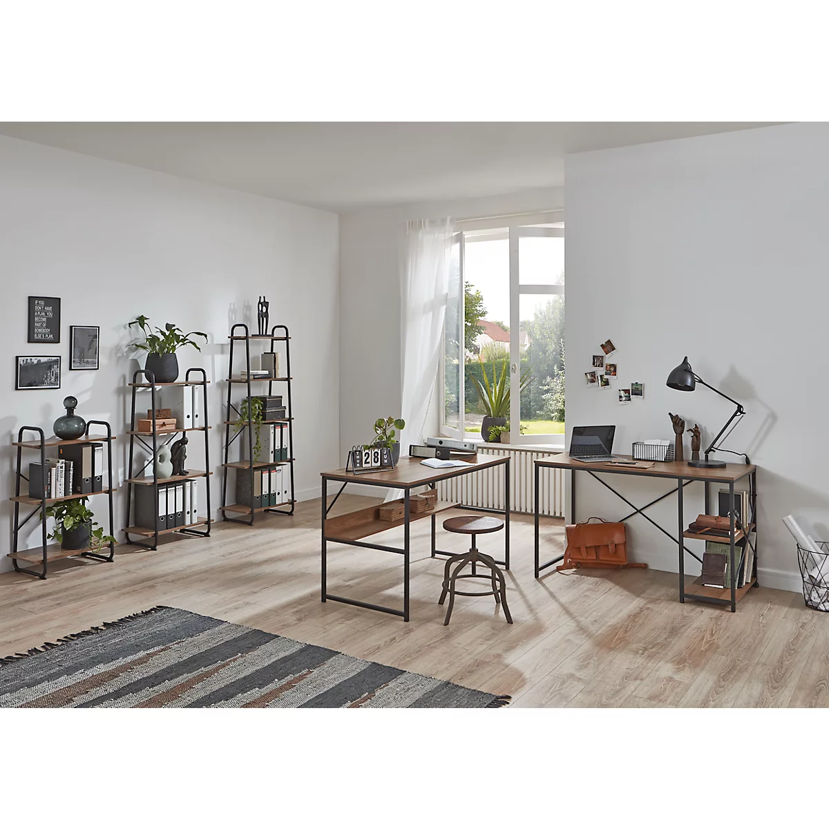 Büro mit Schreibtischen, Regalen und Stuhl. Holz und Metall. Fenster mit Blick ins Grüne. Natürliche, helle Atmosphäre.