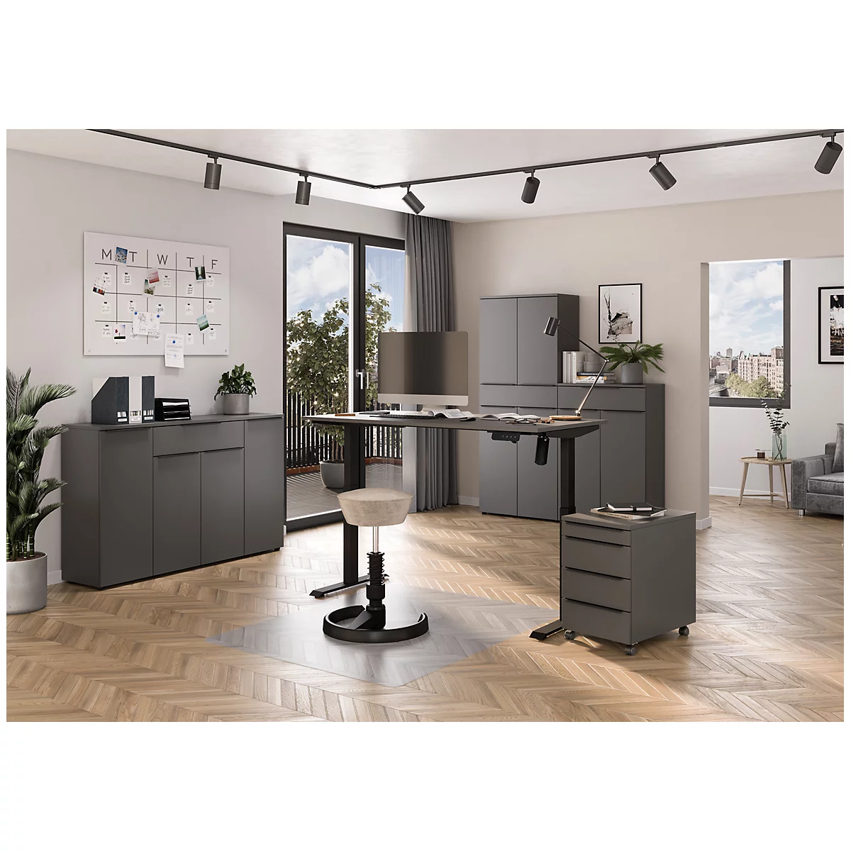 Ein modernes Büro mit dunklen Möbeln. Ein Schreibtisch steht vor einer Balkontür, ein Drehhocker davor. Eine Pinnwand und Pflanzen schmücken den Raum.