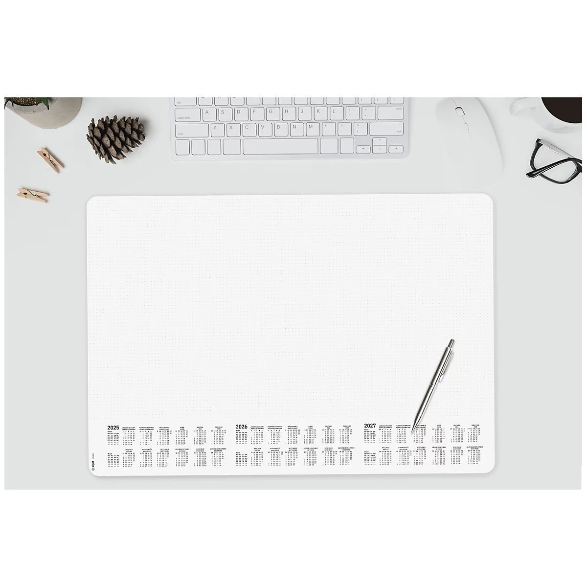 Weißes Mousepad mit Jahreskalendern, Stift, Tastatur, Brille, Tasse und Tannenzapfen auf dem Tisch.