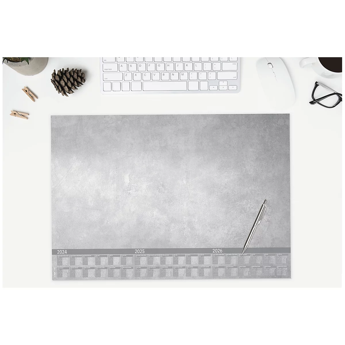 Grauer Schreibtischunterlage mit Jahresübersicht, Stift, Tastatur, Maus, Brille, Kaffeetasse, Deko und Klammern. Von oben fotografiert.