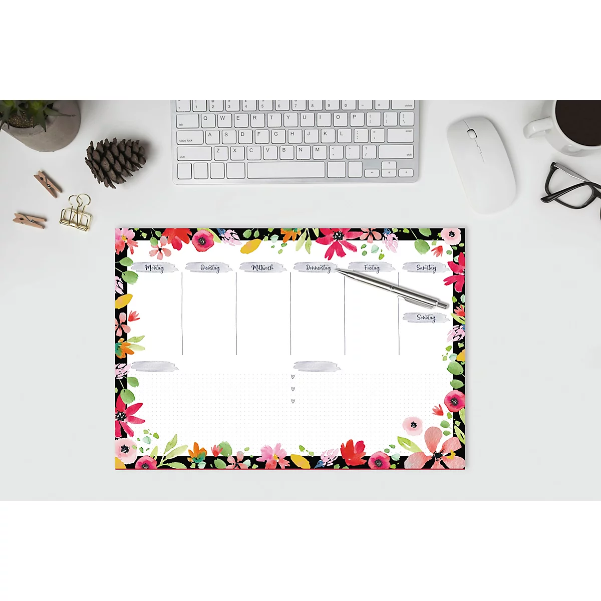 Blumenmuster Wochenplaner mit Wochennamen. Stift liegt auf dem Papier. Tastatur, Maus und Brille im Hintergrund.