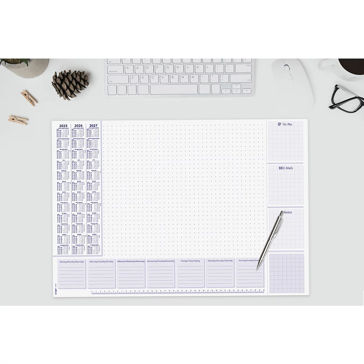 Hellgraue Schreibtischunterlage mit Kalender, Notizblöcken, karierten Feldern und einem Raster. Stift liegt auf der Unterlage.