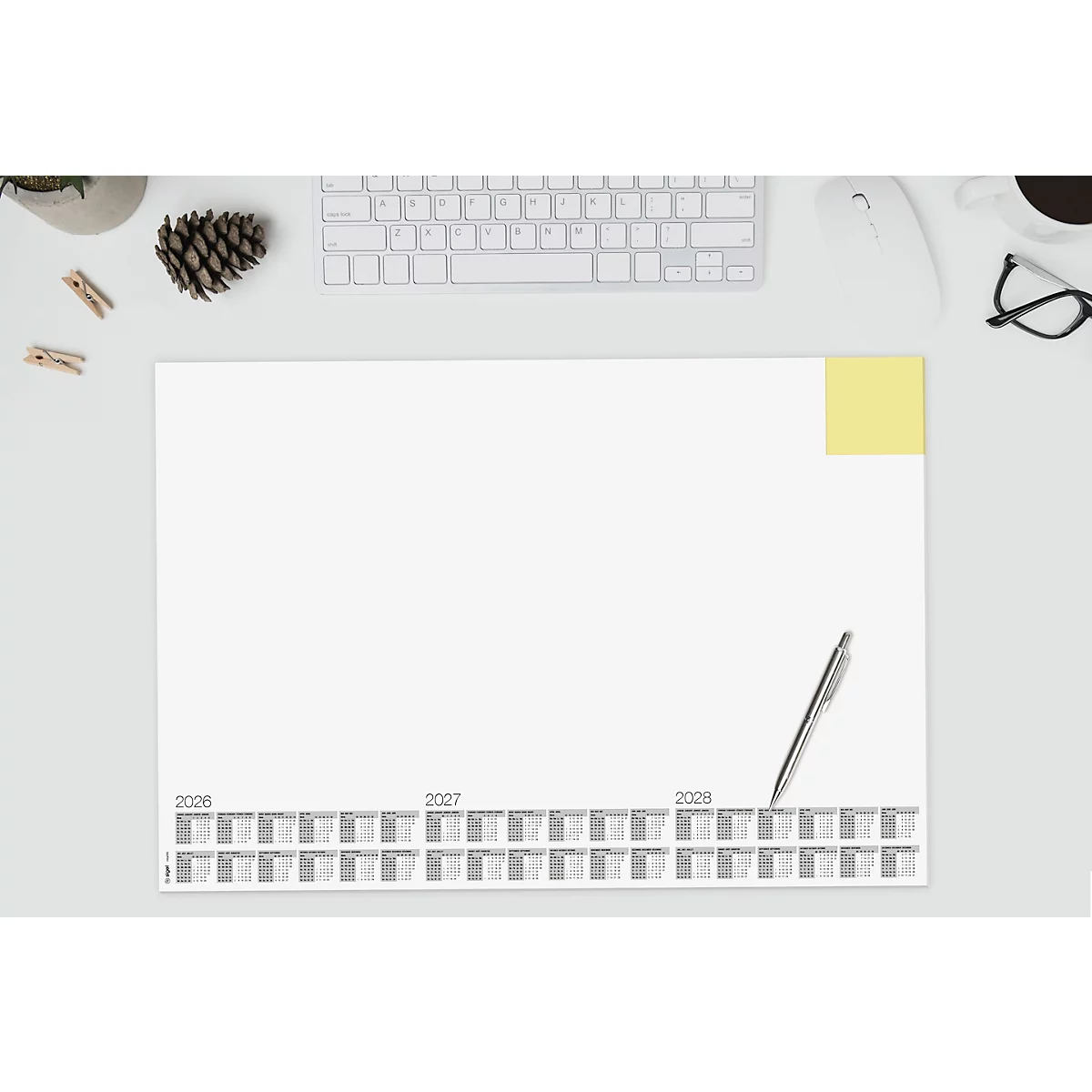 Draufsicht auf einen Schreibtisch mit einem Kalender, einer Tastatur und einer Kaffeetasse. Der Kalender ist für die Jahre 2026-2028 vorgesehen.