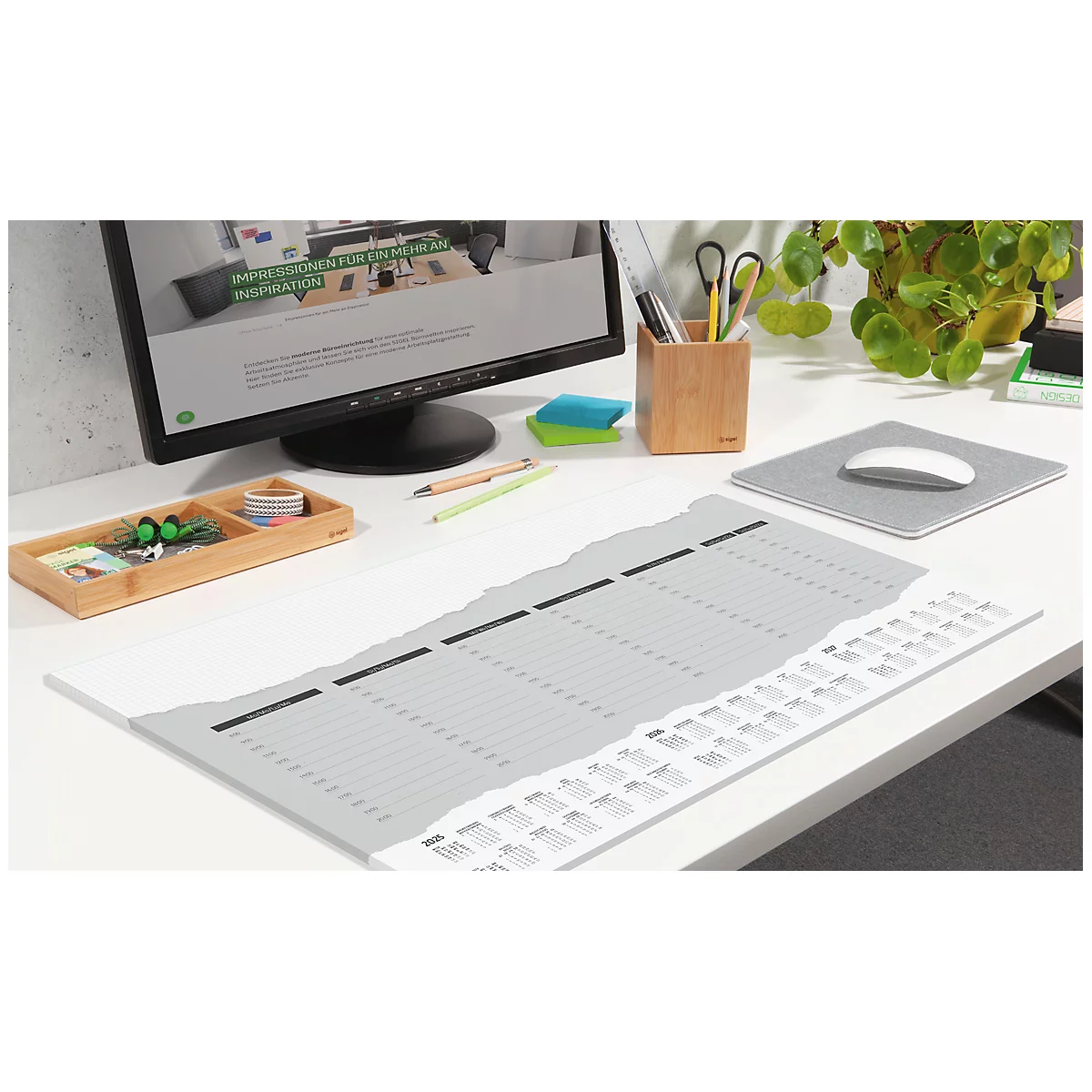 Bureau met kalender, computer, potloodhouder en muismat. De kalender heeft een gescheurde rand en de datum is zichtbaar.