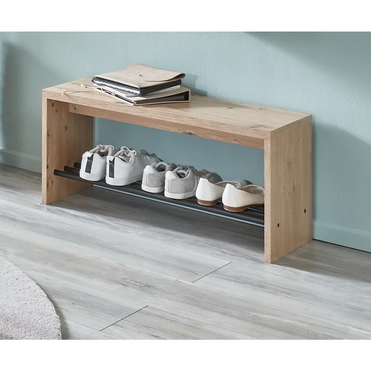 Holzschuhregal mit Büchern und Schuhen. Helle Holzoptik, schwarze Ablage, helle Schuhe.