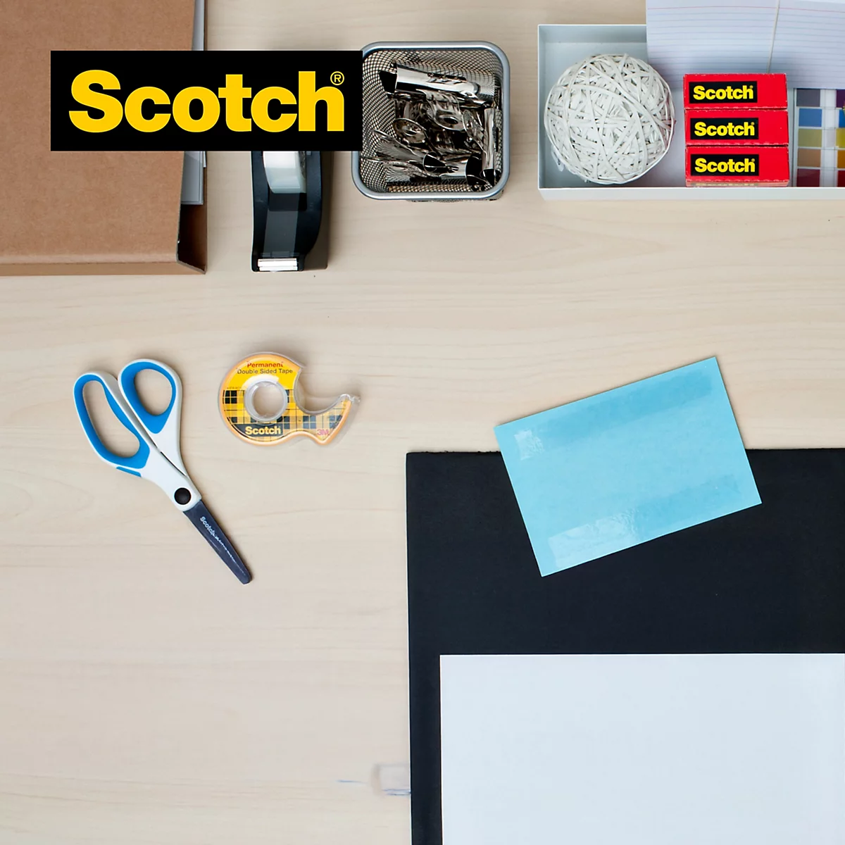 Schreibtisch mit Büroartikeln, darunter Klebeband, Schere und Notizzettel. Text: Einfache Anwendung dank beidseitiger Klebstoff-Beschichtung.