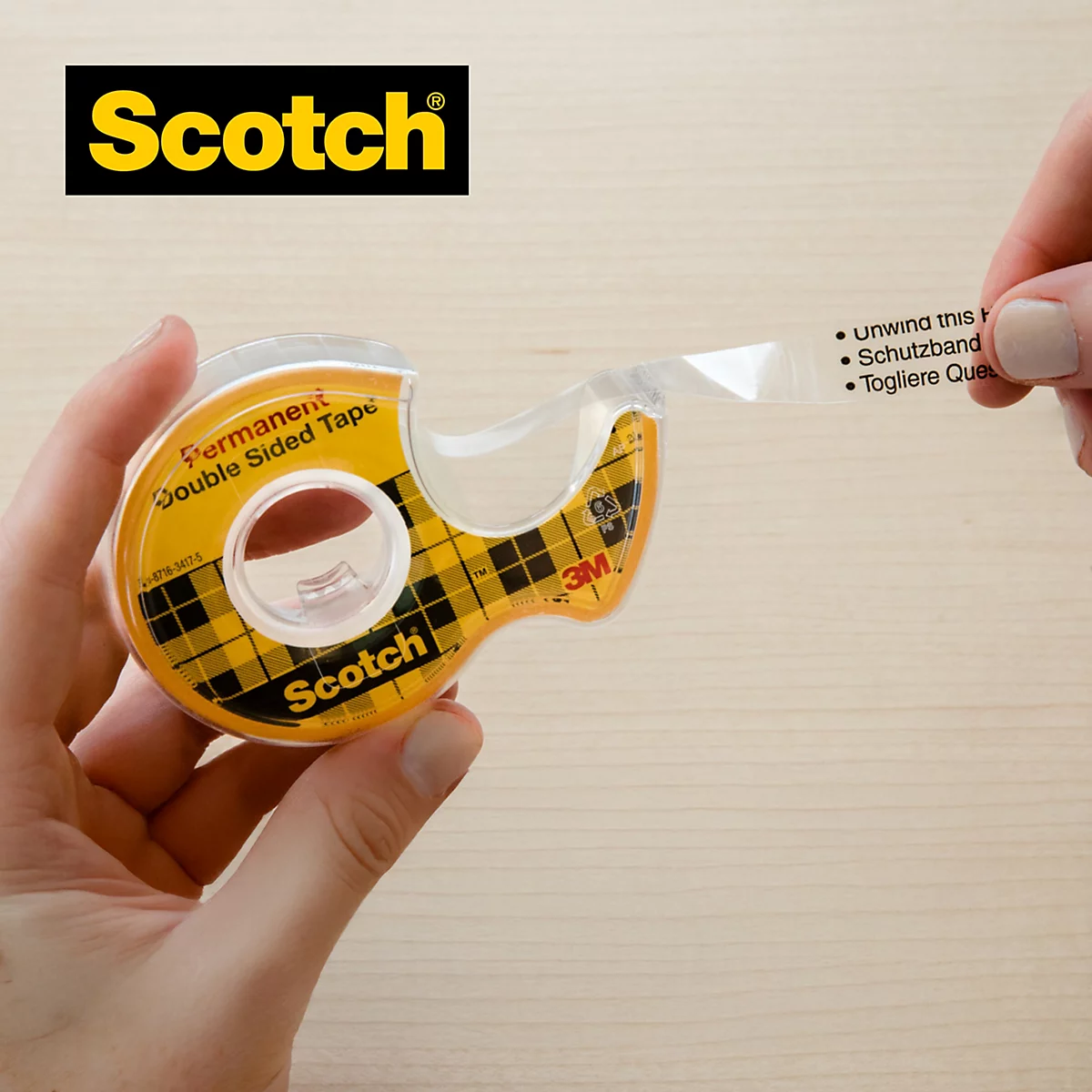 Eine Person hält einen Scotch-Doppelklebeband-Abroller, der gerade Klebeband abrollt. Der Schriftzug "Abroller sorgt für einfache Handhabung" ist zu sehen.