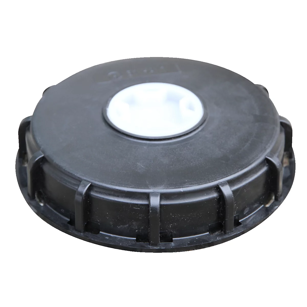 Black plastic lid with white insert in the middle, photographed from above.